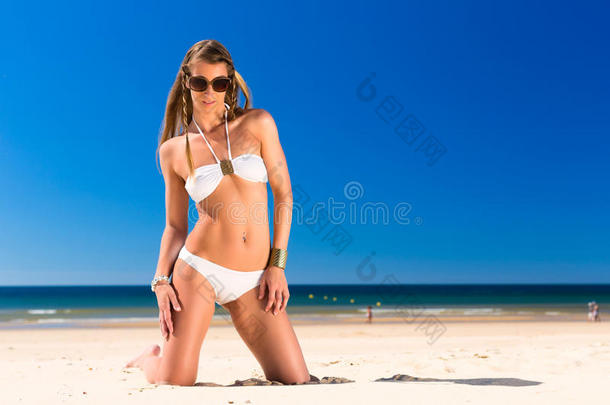 美女跪在沙滩上晒太阳