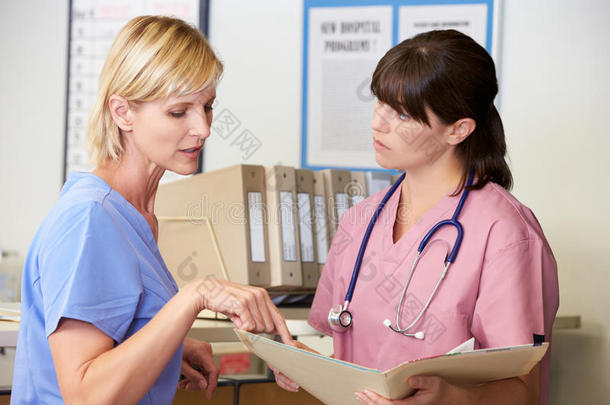 两名护士在护士站讨论病人笔记
