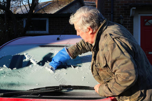 一个男人正在<strong>擦车</strong>窗上的冰。