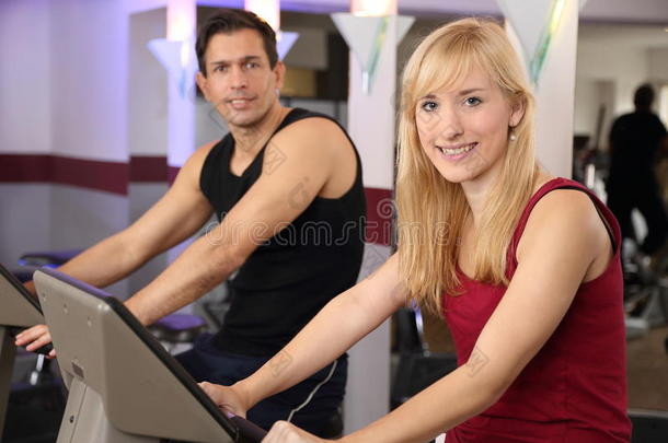 迷人的女人和男人在健身房里骑车