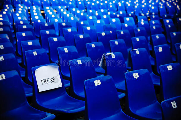 一排蓝色的空椅子，放在会议厅里供记者使用