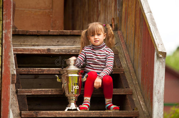 可爱的小女孩坐在俄罗斯萨莫娃附近摆姿势