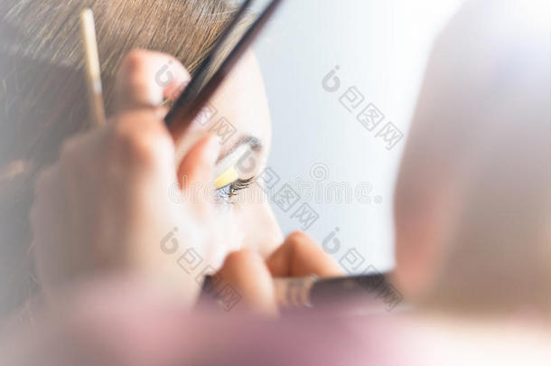 年轻漂亮的女人正在用刷子化妆。
