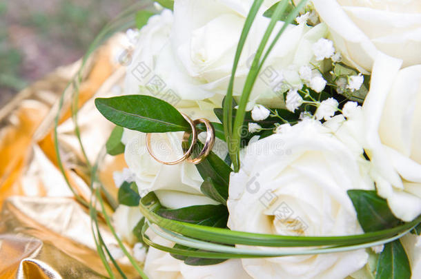 一束白玫瑰，白色玫瑰上有金色结婚戒指的特写镜头