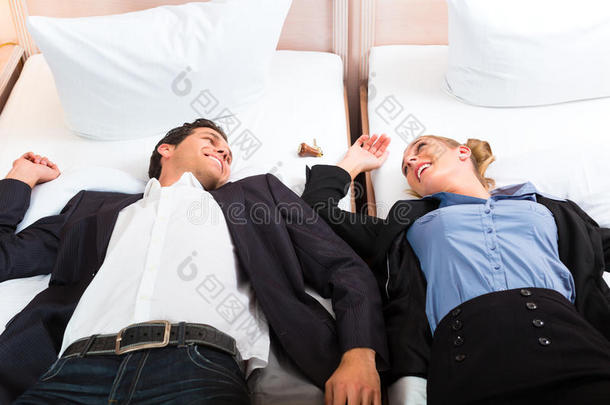 一对年轻夫妇躺在旅馆房间的床上