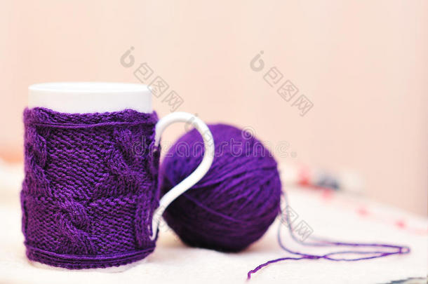 白色杯子，上面有紫色针织毛衣，上面有一团纱线
