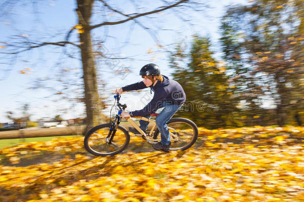 小男孩骑着土车穿过秋天的树叶