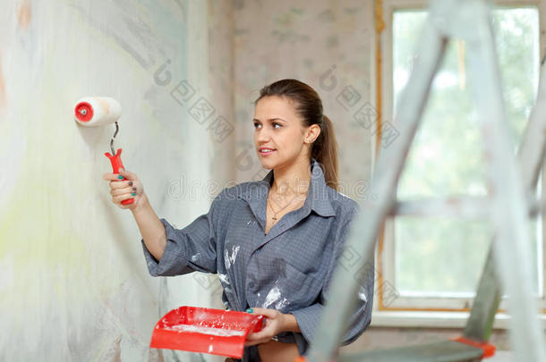 女人用滚筒粉刷墙壁