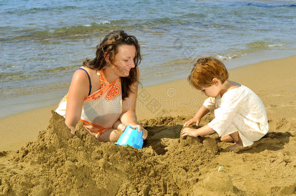 妈妈和女儿在沙滩上玩玩具和沙子