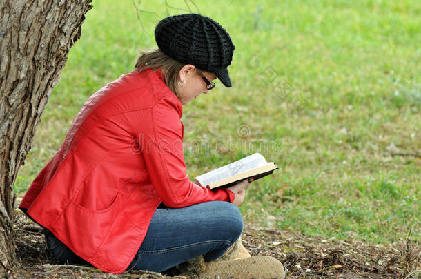 年轻漂亮的少女在大树下看书