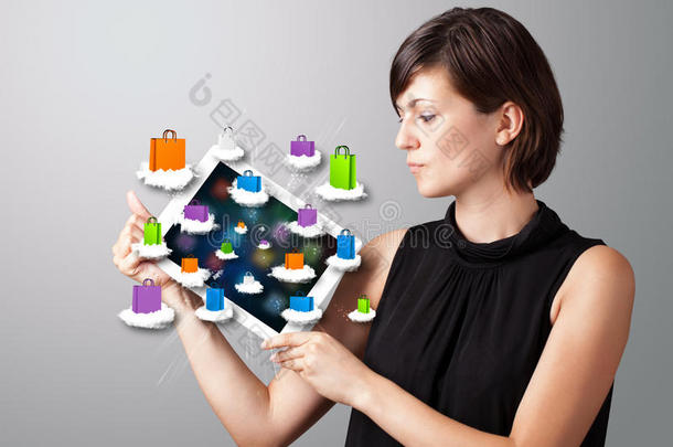 手持现代平板电脑的女人在<strong>云端</strong>挂着五颜六色的购物袋