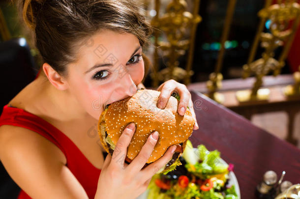 年轻女子在高级餐厅吃汉堡
