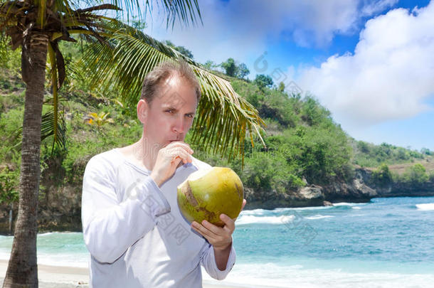 迷人的男人从海边的坚果中喝<strong>椰子汁</strong>