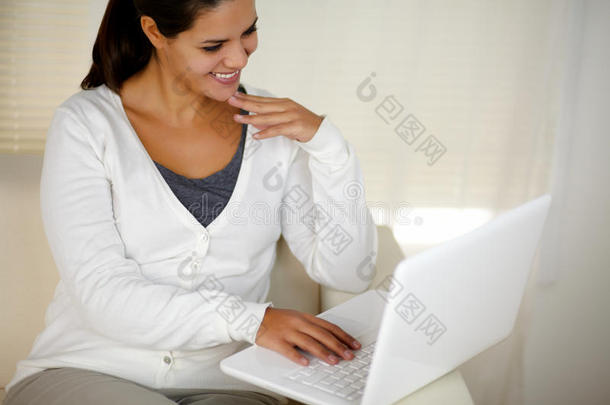 <strong>坐在沙发上</strong>用笔记本电脑的年轻<strong>女子</strong>