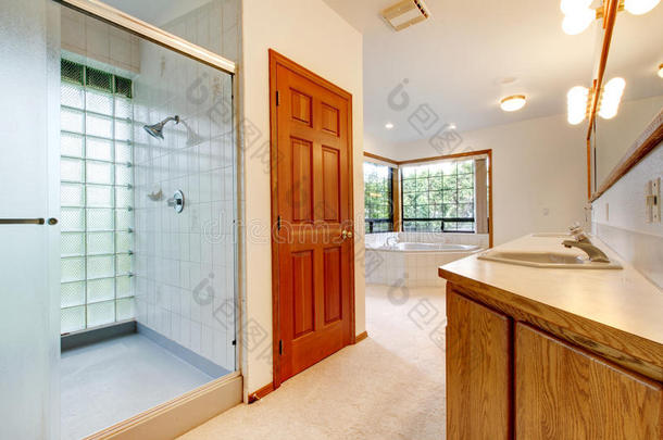 带浴缸、淋浴和木柜的白色大浴室。