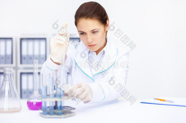 年轻的化学女研究员拿着小瓶和烧瓶在实验室做实验