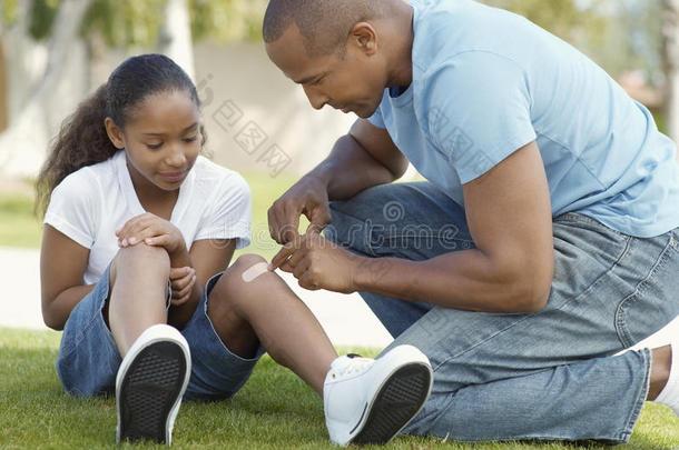 父亲在公园给女儿的膝盖贴绷带