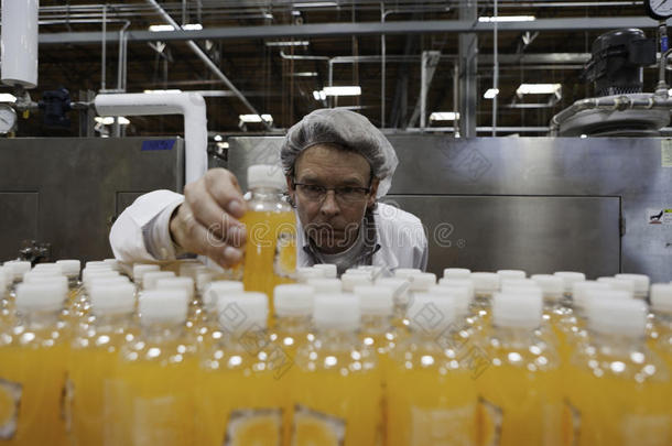 质检人员在生产线上检查果汁瓶