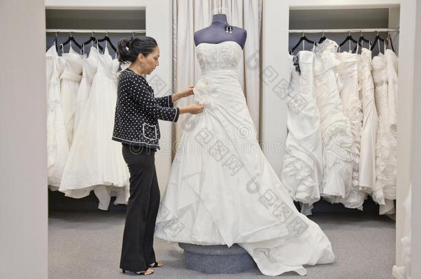 成熟员工在婚纱店调整优雅婚纱侧视图
