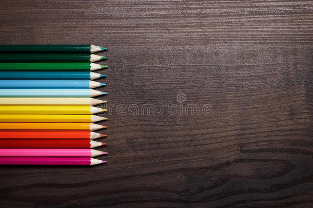 棕色桌面背景上的彩色铅笔