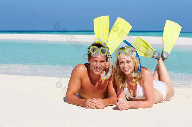 带着潜水器享受海滩度假的情侣们