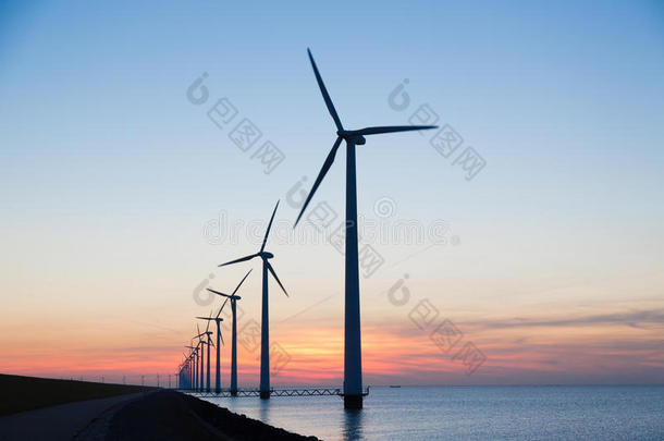 一排<strong>长长</strong>的风力涡轮机，日落在海面上