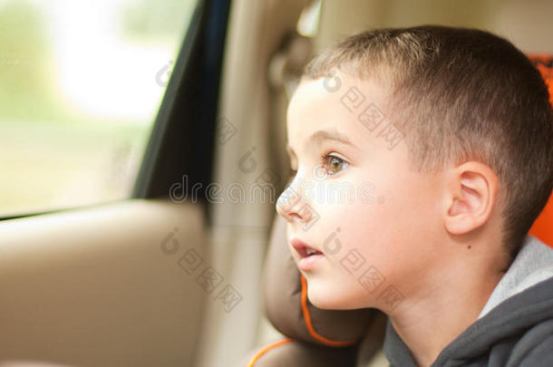 好奇的小男孩在车里看着车窗