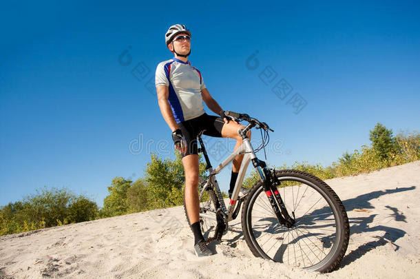 骑自行车的男自行车手在沙地上停了下来