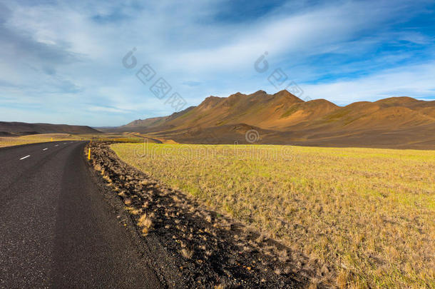 穿过冰岛的公路，在夏日蓝天下的田野景观。