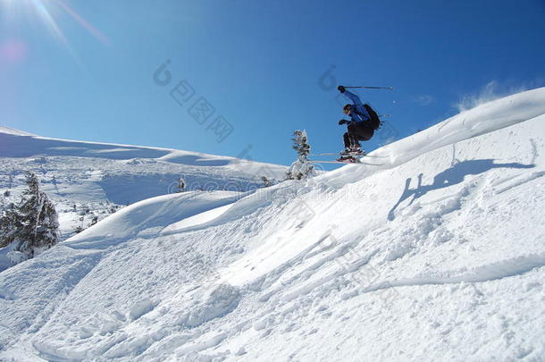 在阳光明媚的冬日滑雪的人。从山上跳高，接着是雪粉。北汽蓝天雪山