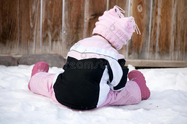 孩子，穿着粉红色衣服的小女孩在冬雪中玩耍。