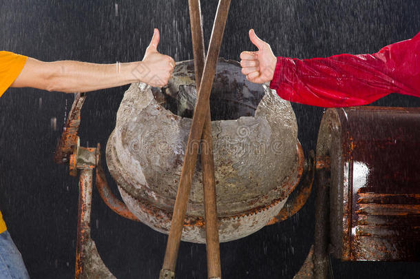 两个工人在水泥搅拌机前竖起大拇指