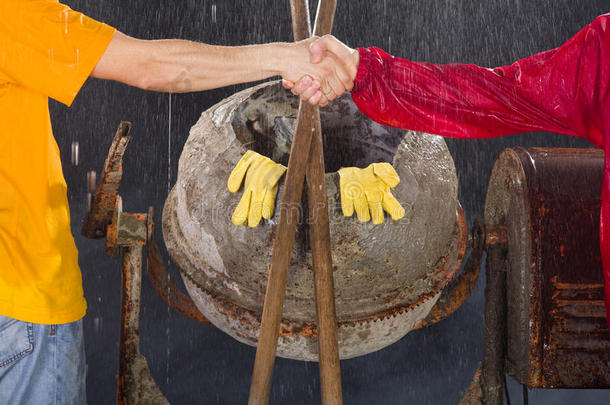 两名工人在水泥搅拌机前握手。