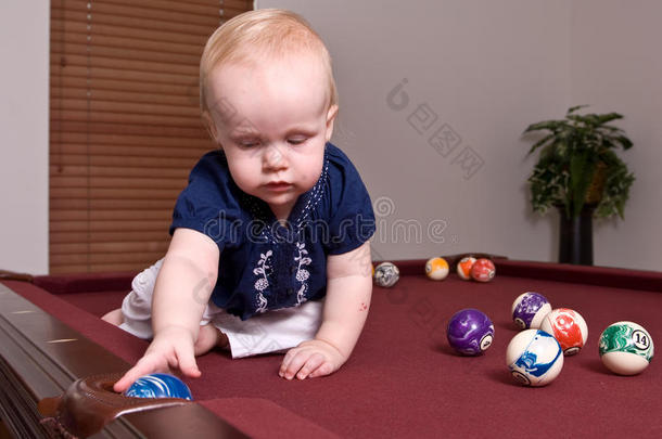 坐在台球桌上把球扔进口袋的小孩