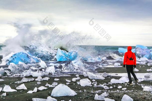 在冰岛东南部瓦特纳冰盖国家公园附近的约卡伦冰川泻湖，一名妇女看着海浪<strong>撞击</strong>冰山