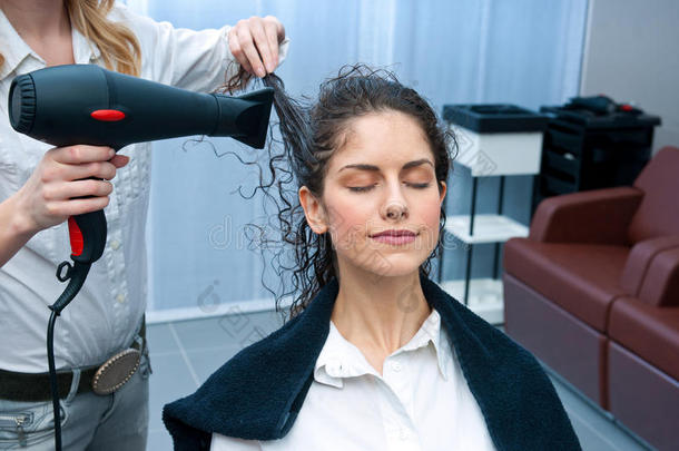 发型师在沙龙里给女人吹干头发