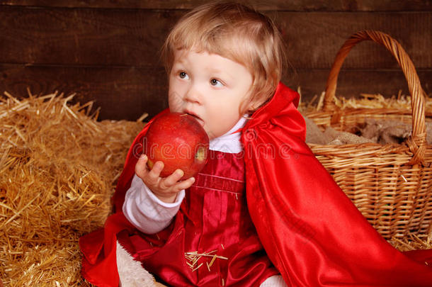 小女孩坐在一堆吃苹果的稻草上。小红