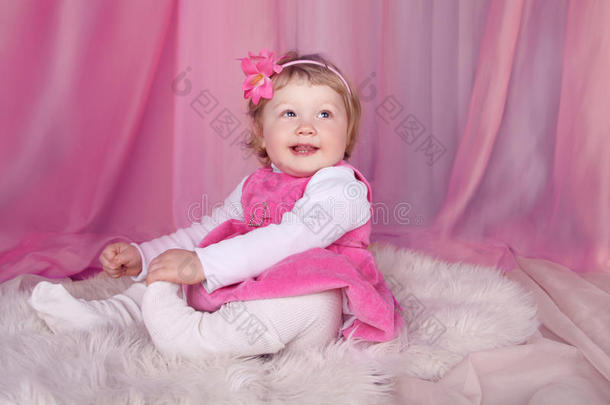 快乐的微笑有趣的小女孩躺在床上粉红色的窗帘上