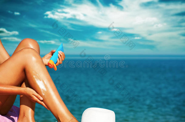 棕褐色女人在腿上涂防晒霜