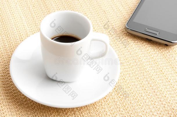 在智能手机附近的杯子里放一杯深咖啡