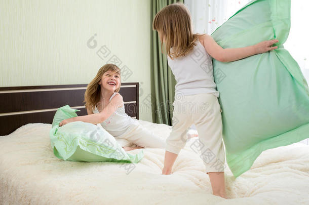 两个小孩或小孩在卧室里玩枕头或和枕头打架