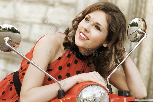 一个年轻的黑发女人坐在一辆旧的红色踏板车上的画像