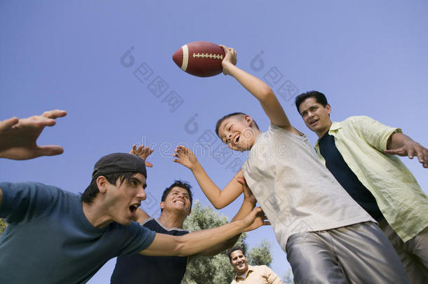 男孩（13-15岁）与一群年轻人一起踢足球低角度观看。