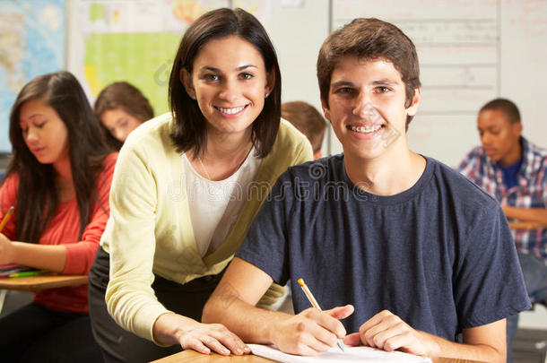 教师帮助男学生在课桌上学习