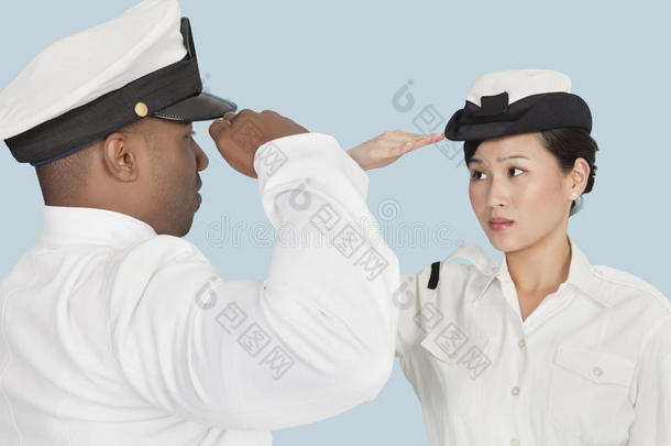 美国海军多民族军官在浅蓝色背景下互相敬礼
