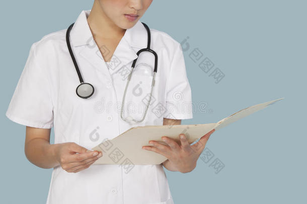 一位女医生在浅蓝色背景下阅读医学报告