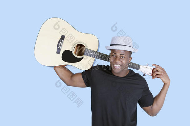 一个<strong>年</strong>轻的非裔美国人拿着吉他在浅蓝色背景上的画像