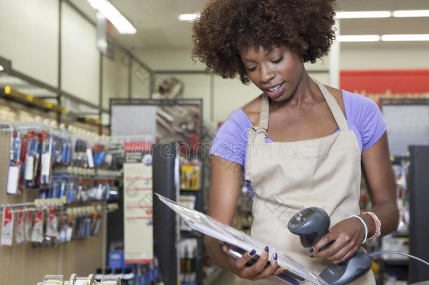 一位非裔美国女店员站在收银台扫描商品的画像