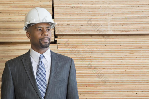 自信的非裔美国男承包商站在堆积<strong>如山</strong>的木板前望向别处