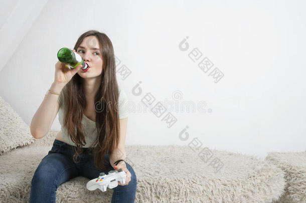 年轻女子边玩电子游戏边喝啤酒